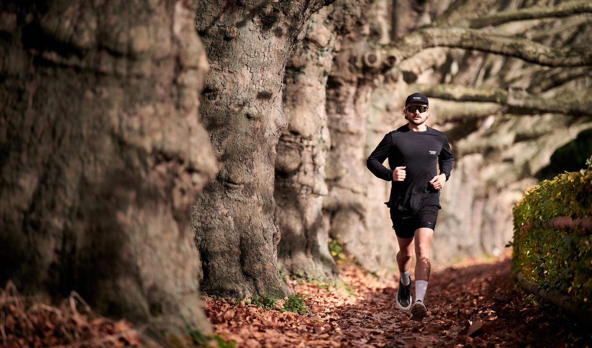Runner on a leaf covered trail under old beech trees